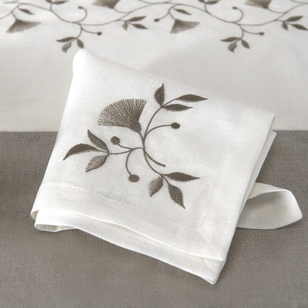 Off-white napkin with brownish floral stitching