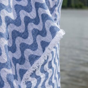 Linen beach towel in blue and white wavy stripes, with fringes