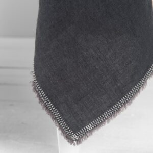 linen grey tablecloth with decorative seam and loose fringes.