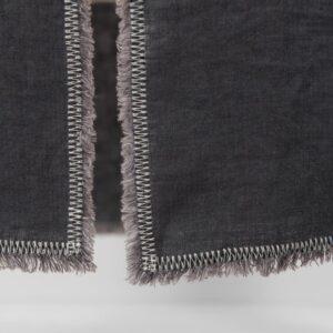 grey linen runner with decorative stitch with loose fringes.